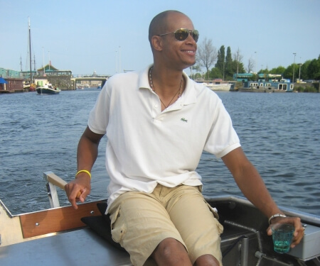 Man navigates a boat on the Amsterdam canals.
