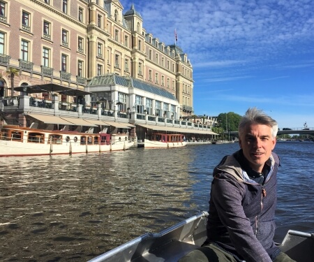 Man in boat in front of the Amstel Hotel in Amsterdam Man in boat in front of the Amstel Hotel in Amsterdam