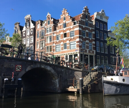 Amsterdam canal houses with bridge and boat.