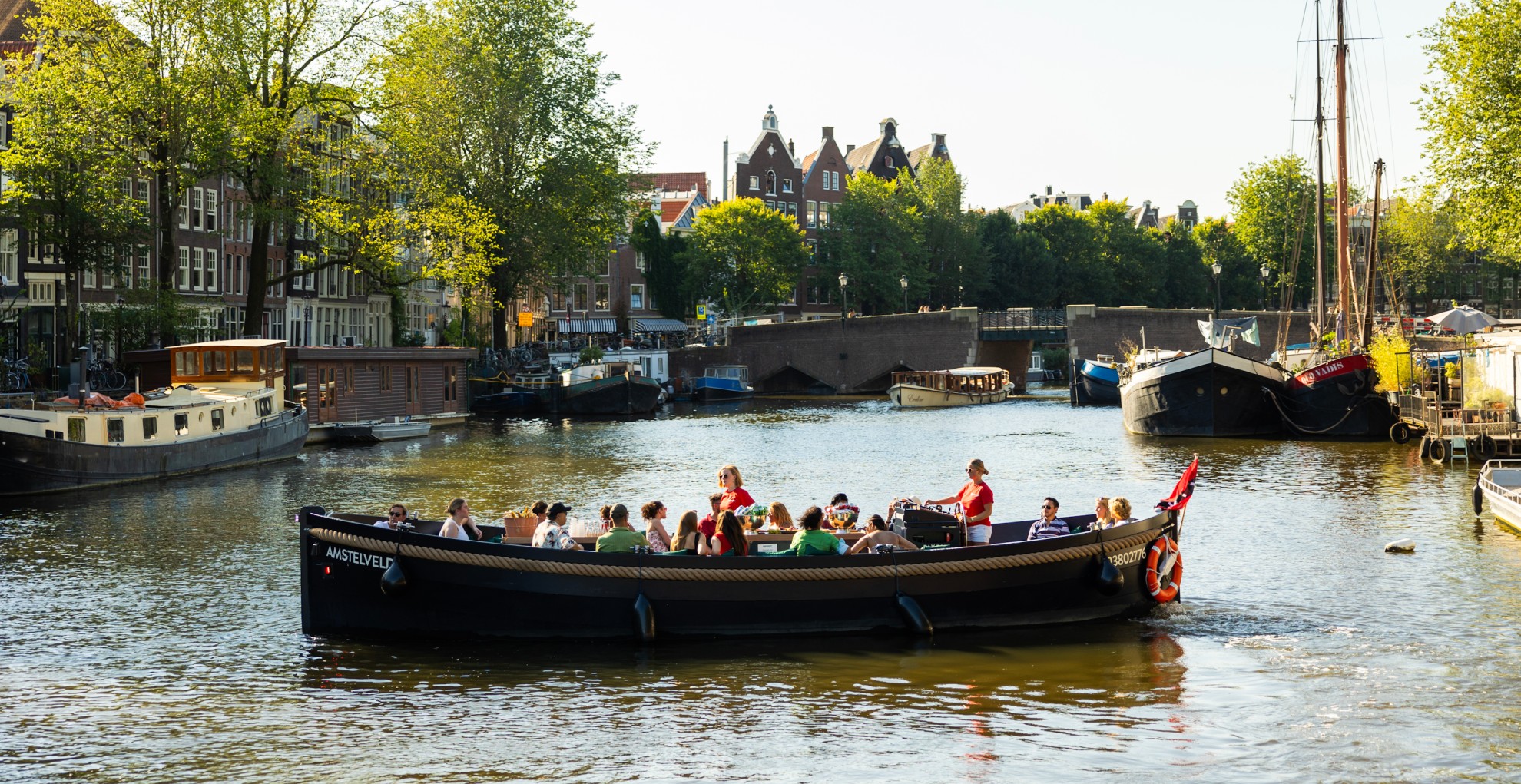 Boaty.nl - Prive rondvaart op een open boot over de Amsterdamse grachten Open boat with a group of people sailing through the Amsterdam canals.